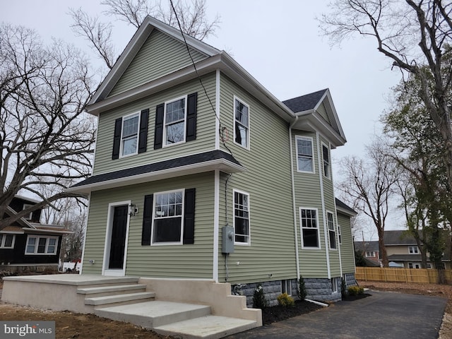 view of front of property featuring fence and a shingled roof