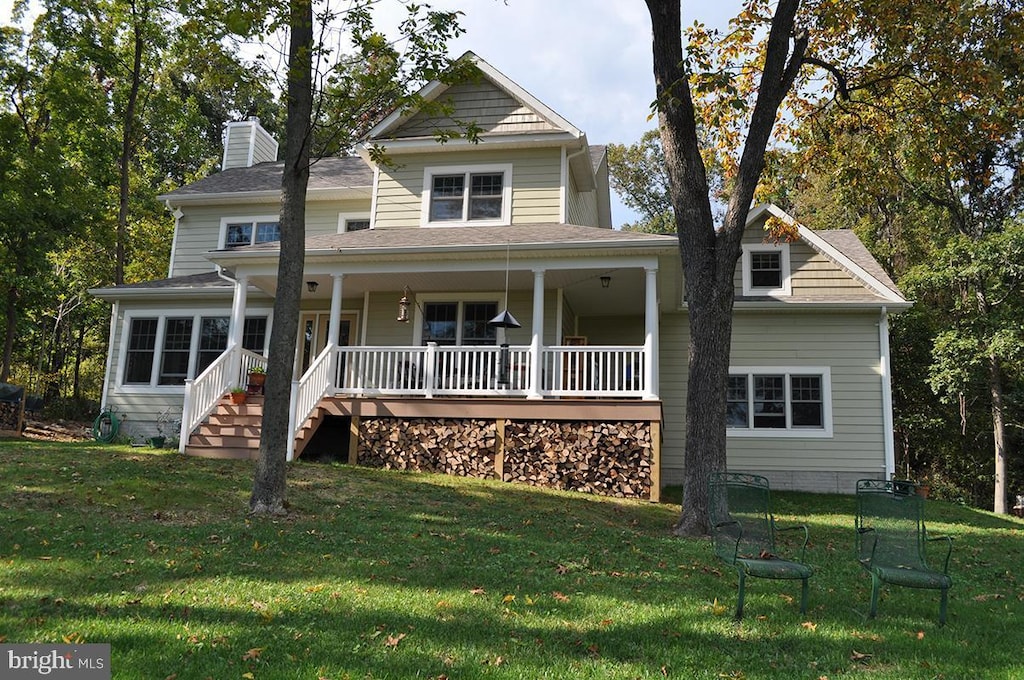 view of front of property featuring a chimney, covered porch, and a front yard