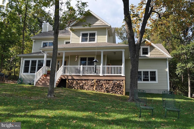 view of front of property featuring a chimney, covered porch, and a front yard