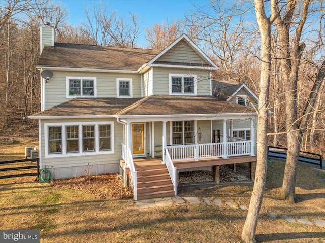 view of front of house with a front yard, roof with shingles, a porch, and a chimney