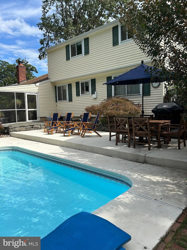 pool with area for grilling, a patio, and a sunroom