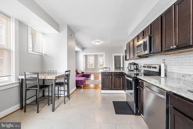 kitchen with tasteful backsplash, stainless steel appliances, baseboards, light stone countertops, and dark brown cabinetry
