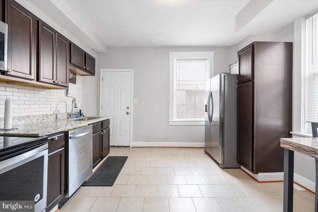 kitchen featuring tasteful backsplash, baseboards, a sink, dark brown cabinetry, and appliances with stainless steel finishes
