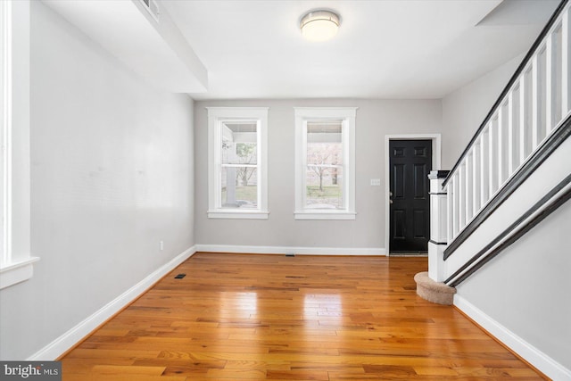 entrance foyer featuring baseboards, light wood-type flooring, visible vents, and stairway