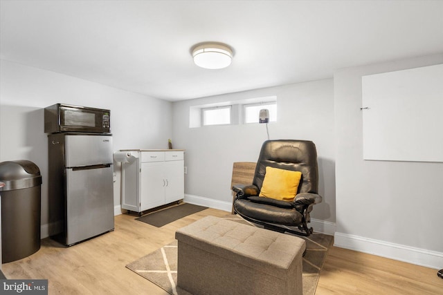sitting room with baseboards and light wood finished floors