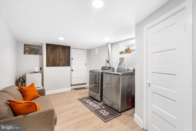 laundry room with light wood-style flooring, independent washer and dryer, baseboards, and laundry area