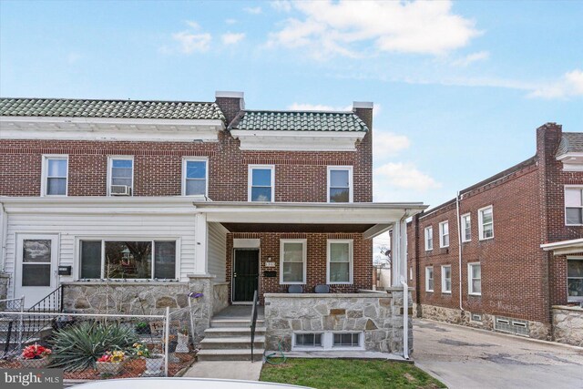 view of front of property featuring brick siding, fence, and covered porch