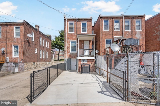 view of front facade featuring a gate, fence, concrete driveway, and brick siding