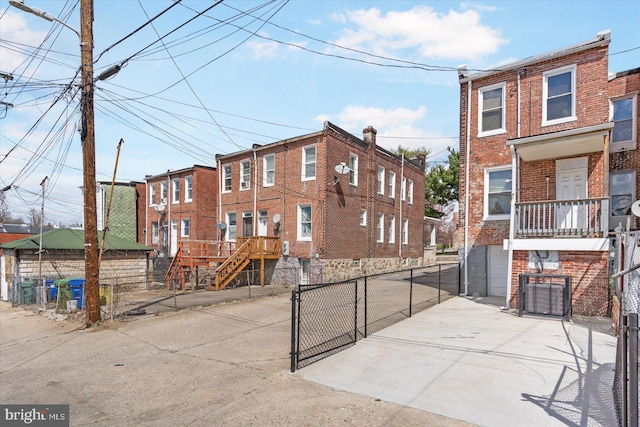 exterior space with brick siding, driveway, and fence