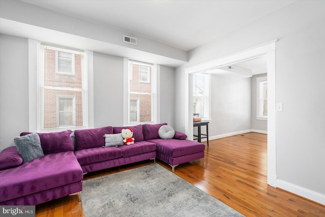 living area featuring baseboards, visible vents, and wood finished floors