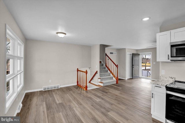 kitchen with white cabinetry, visible vents, light wood finished floors, and stainless steel appliances