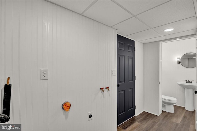 bathroom with toilet, wood finished floors, and a drop ceiling