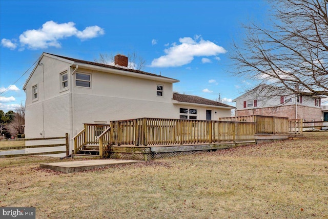 rear view of house with a wooden deck, a lawn, a chimney, and fence