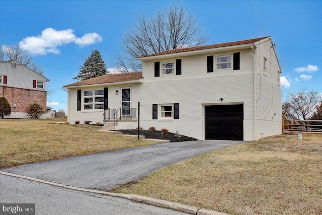 tri-level home with a front yard, an attached garage, brick siding, and driveway