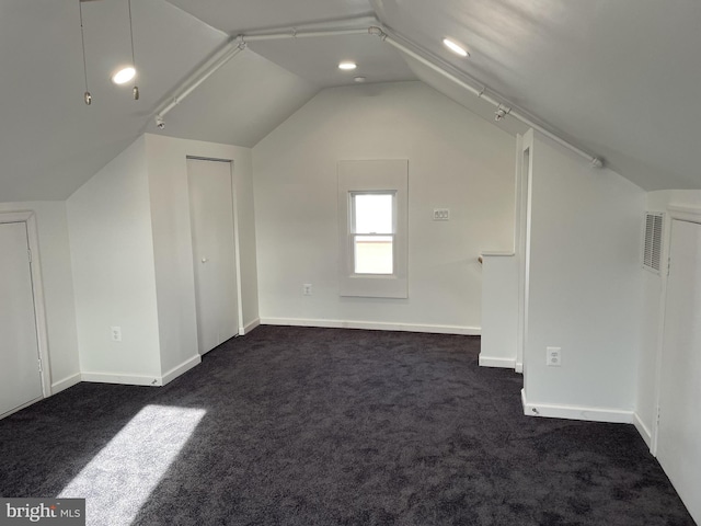 bonus room with vaulted ceiling, visible vents, and dark carpet