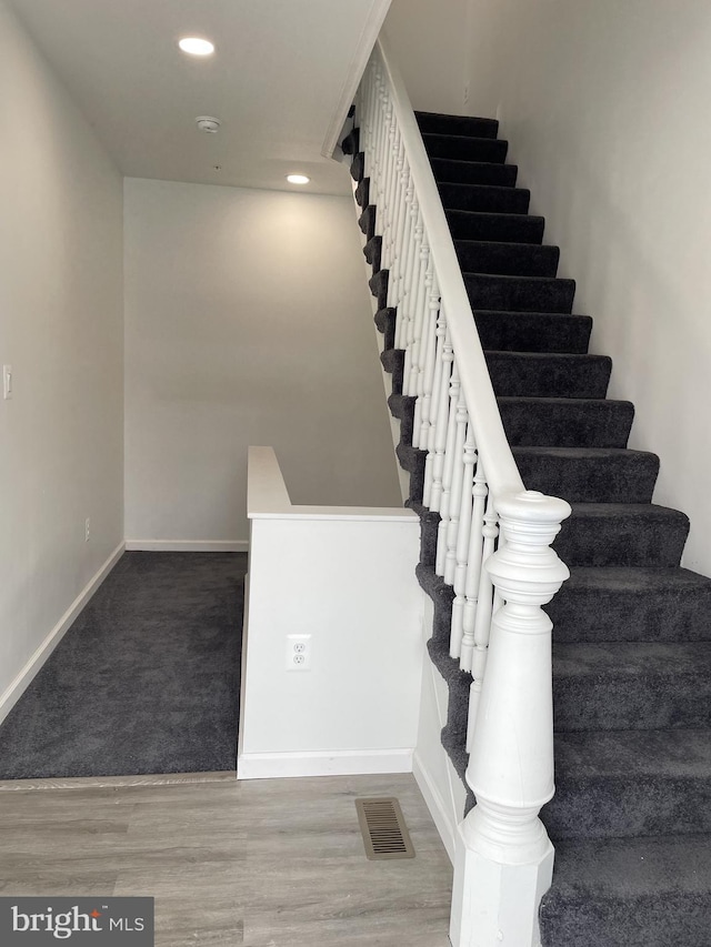 stairway with recessed lighting, visible vents, baseboards, and wood finished floors