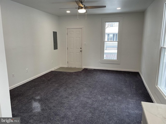 empty room featuring a ceiling fan, baseboards, electric panel, recessed lighting, and dark carpet