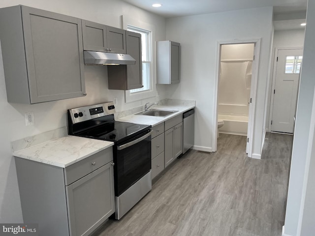 kitchen with under cabinet range hood, stainless steel appliances, gray cabinets, and a sink