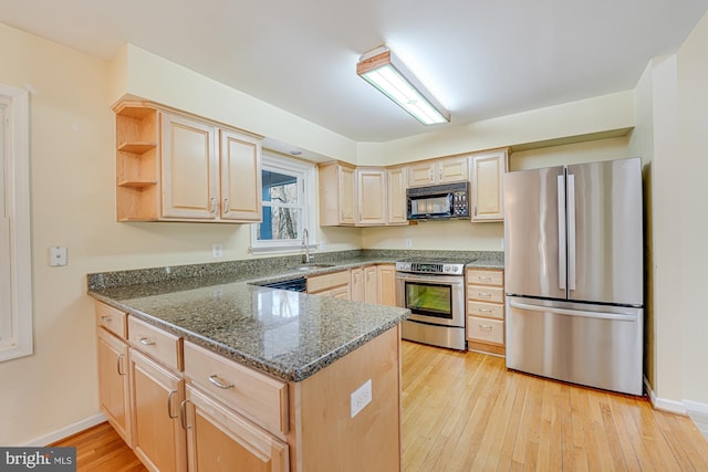 kitchen featuring stainless steel appliances, light wood-style floors, a peninsula, and light brown cabinets