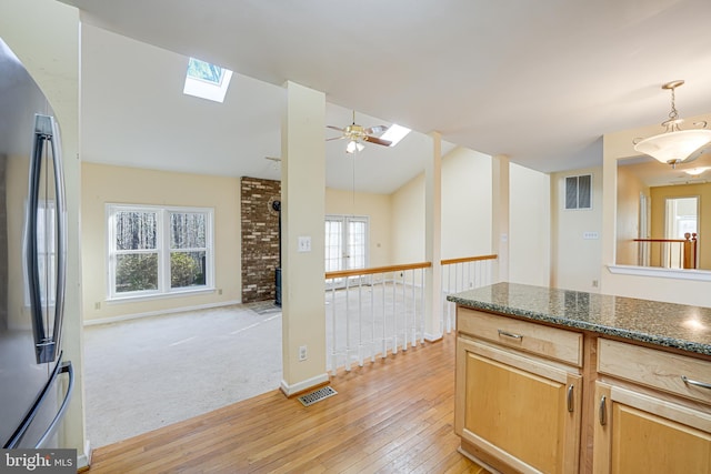 kitchen featuring visible vents, dark stone countertops, open floor plan, freestanding refrigerator, and light wood finished floors