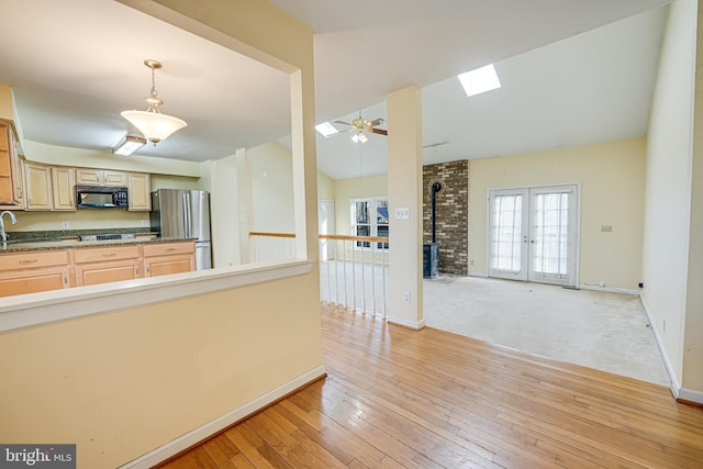 kitchen with light wood finished floors, freestanding refrigerator, a sink, french doors, and black microwave