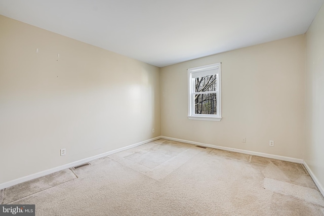 carpeted spare room with visible vents and baseboards