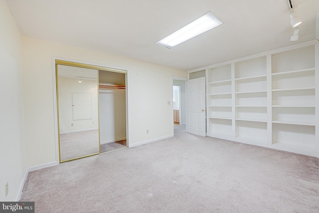 unfurnished bedroom with rail lighting, carpet, and baseboards