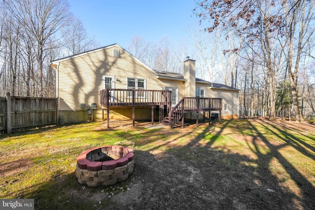 back of property featuring a deck, stairs, an outdoor fire pit, a yard, and a chimney