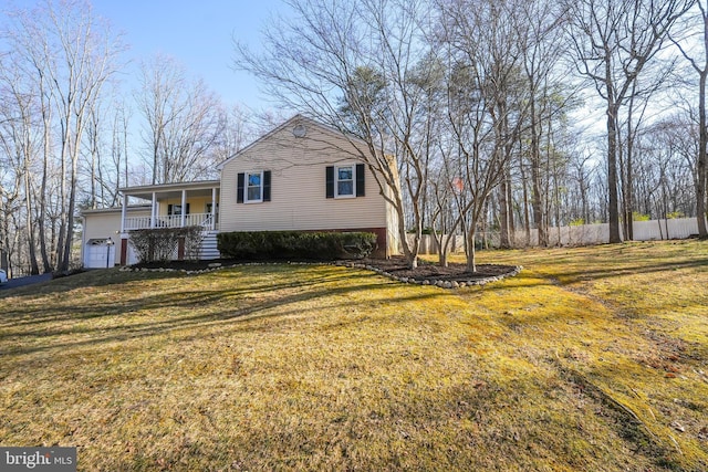 exterior space featuring fence, a garage, a lawn, and covered porch