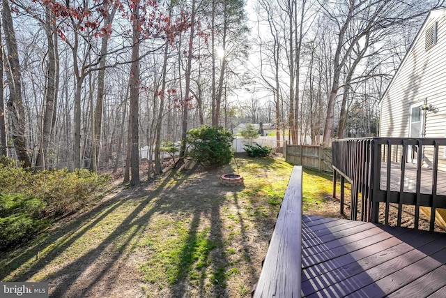 view of yard featuring a deck, fence, and an outdoor fire pit