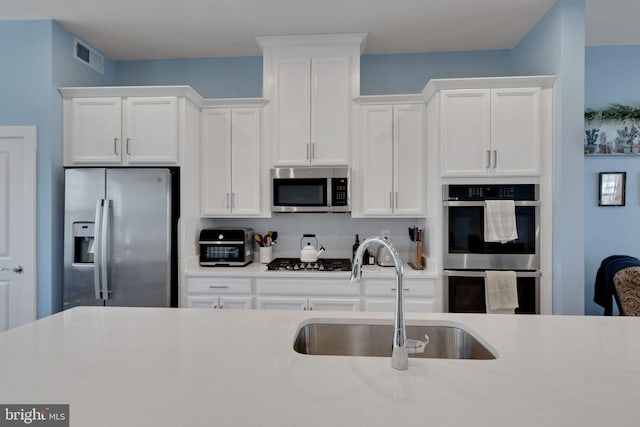 kitchen featuring a sink, stainless steel appliances, light countertops, and white cabinetry