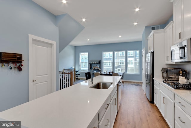 kitchen with a sink, recessed lighting, appliances with stainless steel finishes, white cabinets, and light countertops