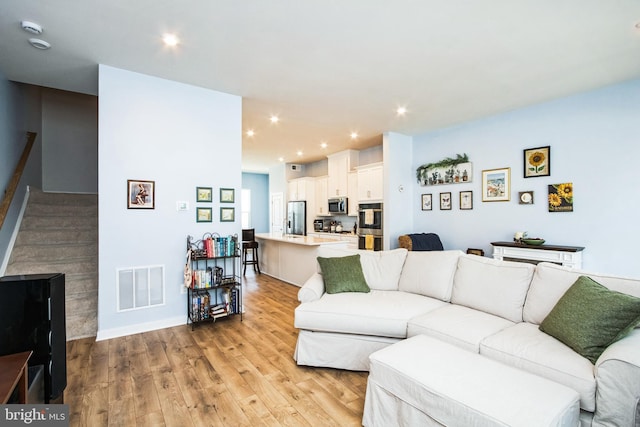 living area with visible vents, recessed lighting, stairway, and light wood-type flooring