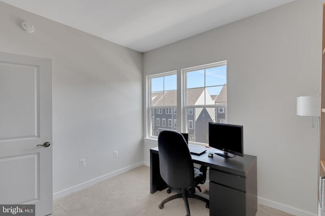 home office with baseboards and light colored carpet
