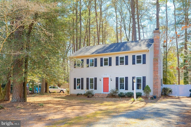 colonial inspired home featuring a gate, fence, and a chimney