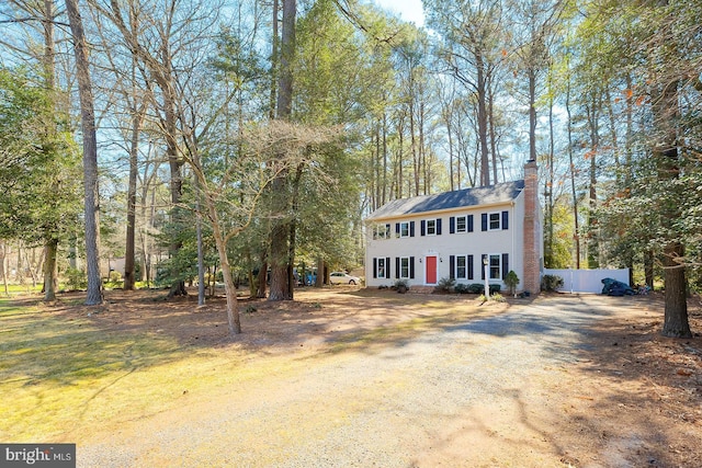 colonial home featuring a chimney and fence