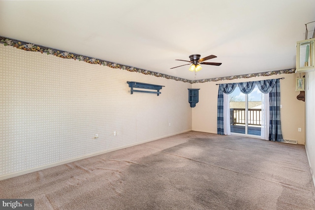 carpeted spare room with wallpapered walls, a ceiling fan, visible vents, and baseboards