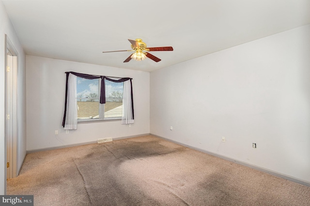 carpeted empty room with visible vents, baseboards, and ceiling fan