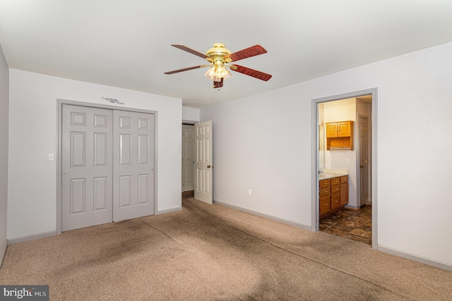 unfurnished bedroom with dark colored carpet, a closet, baseboards, and connected bathroom