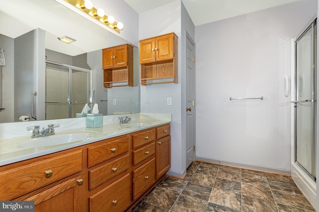 full bath with a shower stall, double vanity, baseboards, and a sink