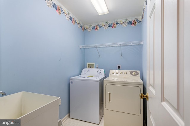 laundry room with laundry area, separate washer and dryer, baseboards, and a sink