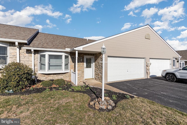 single story home featuring stone siding, driveway, an attached garage, and a shingled roof