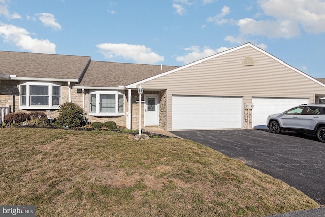 single story home with aphalt driveway, stone siding, a shingled roof, a front yard, and an attached garage