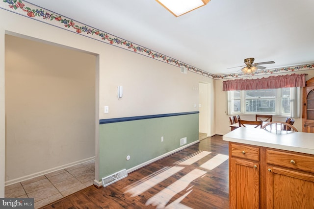 kitchen featuring visible vents, dark wood finished floors, light countertops, baseboards, and ceiling fan