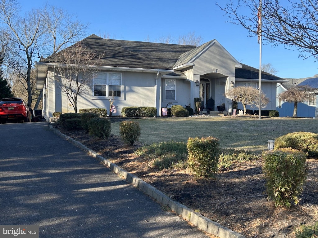 ranch-style home with stucco siding and a front yard