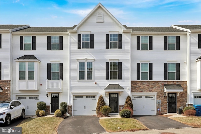 view of property featuring an attached garage, stone siding, and driveway