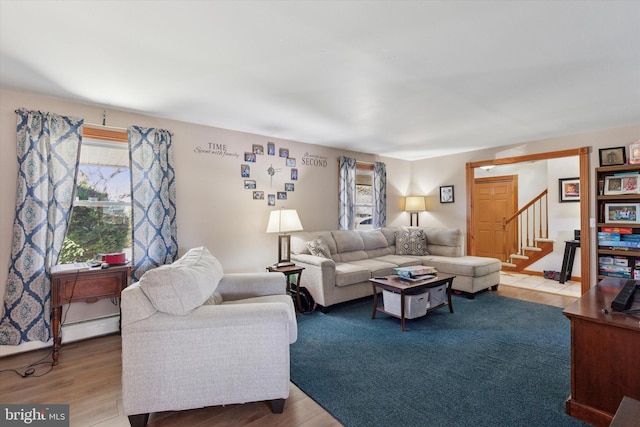 living room featuring light wood-type flooring, stairway, and a baseboard heating unit