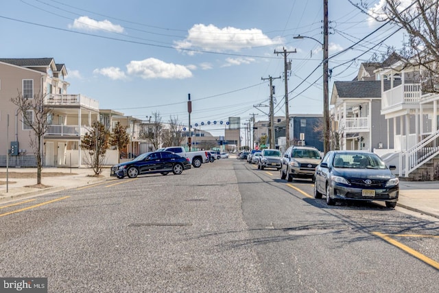 view of road with sidewalks, a residential view, curbs, and street lighting