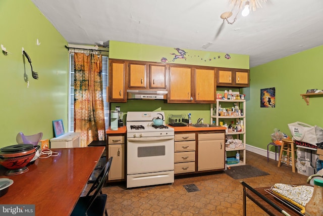 kitchen with a sink, baseboards, under cabinet range hood, white gas range, and open shelves