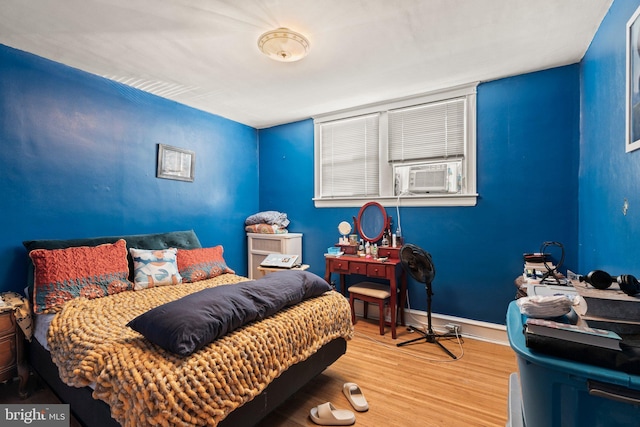 bedroom with cooling unit, wood finished floors, and baseboards